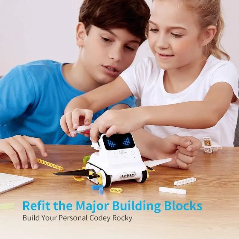 Two children playing with a robot toy on a wooden table.